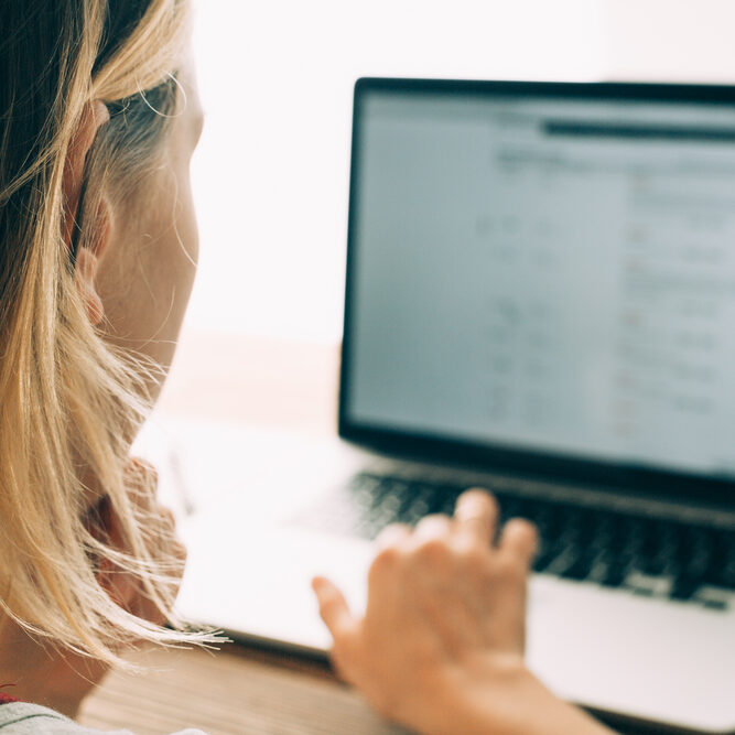 Woman working with laptop placed on wooden desk