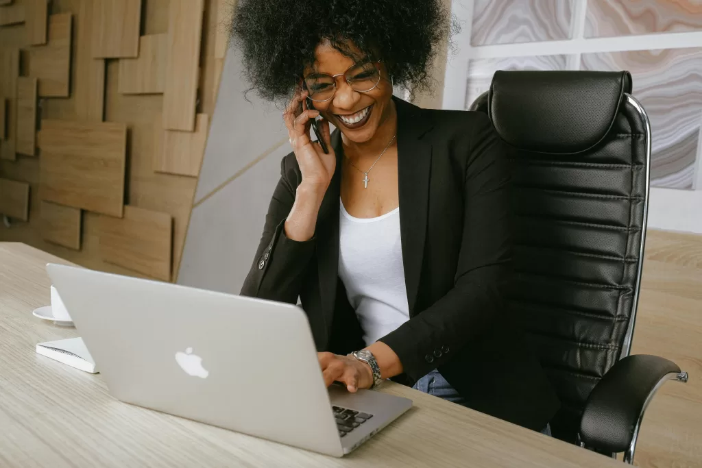 Photograph of woman using cellular phone and laptop.